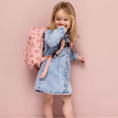 Criança com vestido azul claro e mochila rosa com padrão de animais