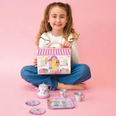Conjunto de chá infantil em tons de rosa e lilás com caixa ilustrada e rapariga sentada a segurá-la