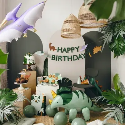Decoração de festa de aniversário com balões de dinossauro e pterossauro, plantas verdes e banner HAPPY BIRTHDAY