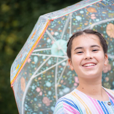 Guarda-chuva transparente com padrão floral colorido e jovem sorridente com camisa listrada