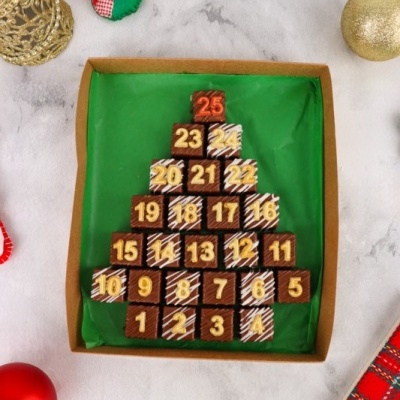 Caixa de chocolates em forma de árvore de Natal com números e enfeites natalinos ao redor