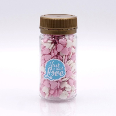 Frasco com confeitos de coração rosa e branco e etiqueta azul dizendo Just add Love