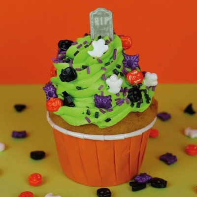 Cupcake decorado de Halloween com cobertura verde e confeitos temáticos coloridos