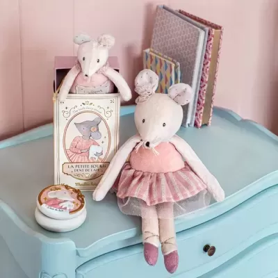 Duas bonecas de rato de tecido cor-de-rosa com vestuário delicado numa cómoda azul clara, uma em caixa decorada e livros ao fundo.