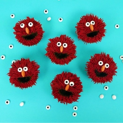 Seis pompons vermelhos com olhos e bocas sobre fundo azul claro