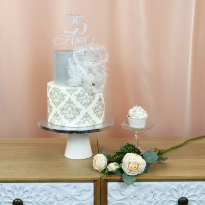 Bolo de 2 andares com decoração floral cinza e topo 25 Anos, cupcake com chantilly e flores em móvel de madeira