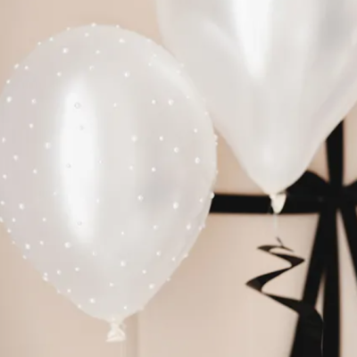 Dois balões brancos, um com pérolas e um liso, com fitas pretas