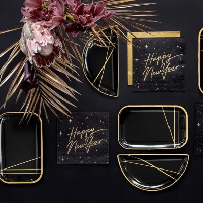 Artigos para festa de Ano Novo com guardanapos e pratos pretos e dourados, com decoração floral