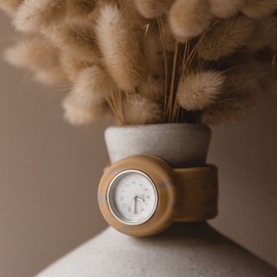 Relógio de silicone castanho em vaso de cerâmica cinzenta com flores secas