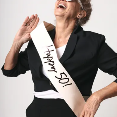 Mulher com faixa branca, óculos de sol em forma de coração e fato preto