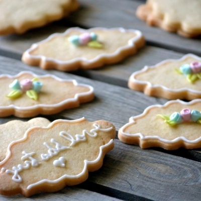 biscoitos decorados com glacê branco e flores coloridas em superfície de madeira