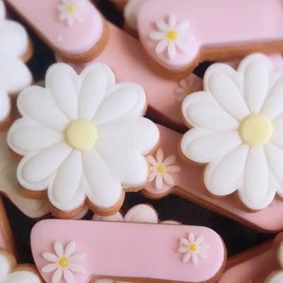 Biscoitos decorados em forma de flor branca e rosa com glacê.