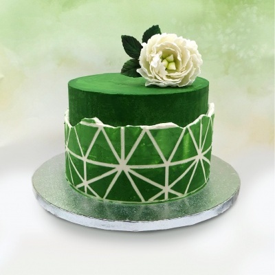 Bolo verde com padrão geométrico branco e flor branca em cima