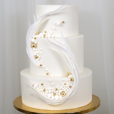 Bolo de três andares branco com pérolas e folhas brancas em fundo branco