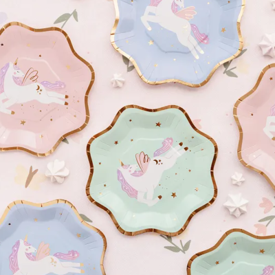 pratos descartáveis coloridos com design de unicórnios e contorno dourado em fundo claro