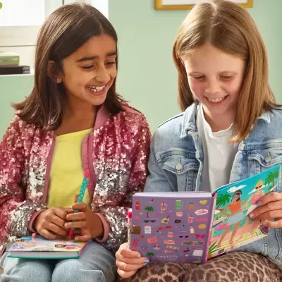Duas meninas sorridentes com casacos coloridos e cadernos ilustrados