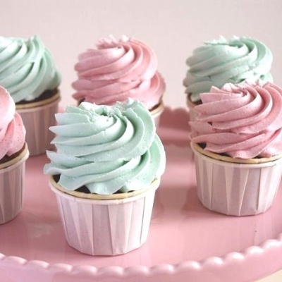 Seis cupcakes com cobertura azul claro e rosa num prato rosa
