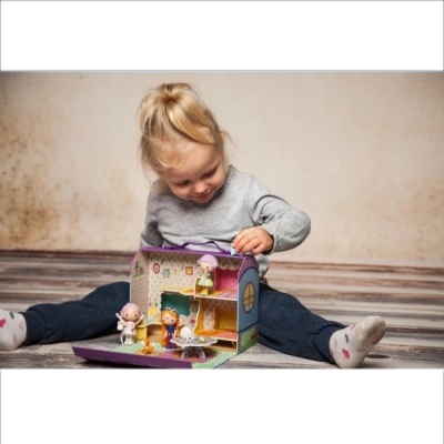 Criança a brincar com casinha de bonecas em cartão colorido com bonecos