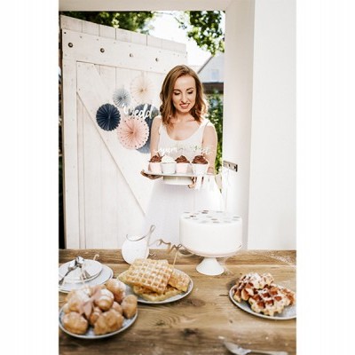 Bolo branco decorado com cerejas e vários doces em mesa rústica com mulher ao fundo