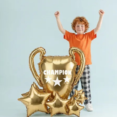 Criança com balões dourados de troféu e forma de estrela