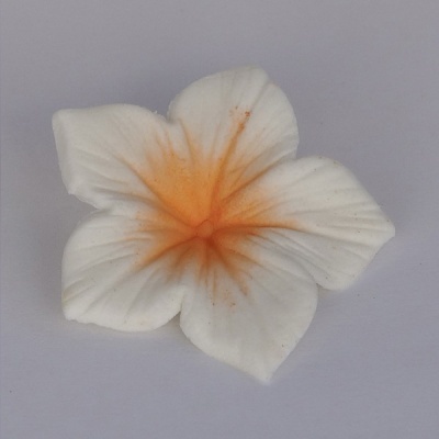 Flor artificial branca com centro laranja e seis pétalas em fundo cinza claro