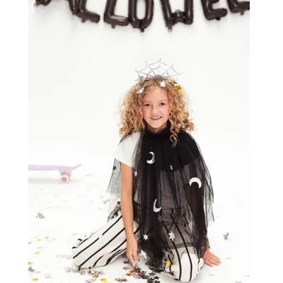 Menina com capa preta de Halloween e calças riscas