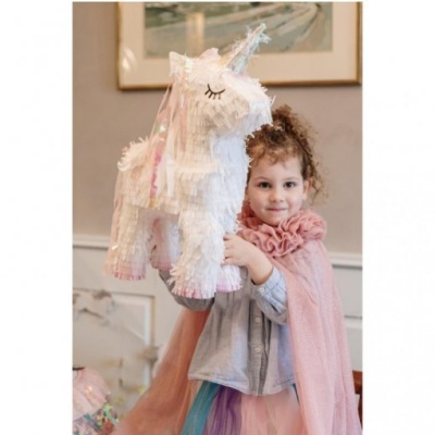 Menina com capa a segurar piñata de unicórnio colorido