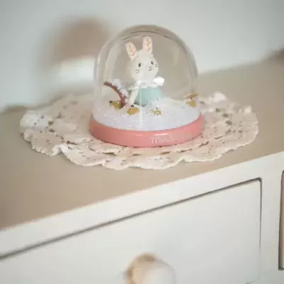 Globo de neve com coelho no interior e base rosa com texto Moulin Roty