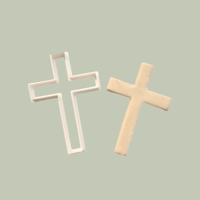 Dois crucifixos, um branco com bordas vazadas e outro bege sólido sobre fundo cinza claro.