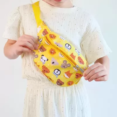 Pochete amarela com estampa de animais em criança com vestido creme.