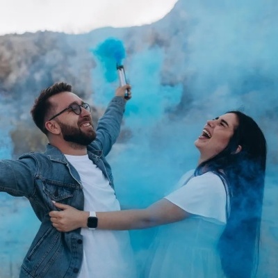 Homem e mulher sorrindo com fumaça azul ao ar livre