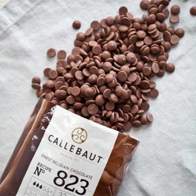 Pacote de chocolate Callebaut 823 com gotas de chocolate sobre tecido cinzento