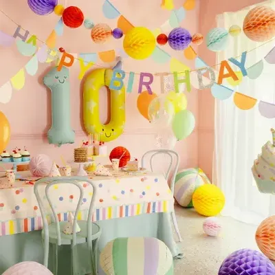 Decoração de festa de aniversário com balões, guirlandas e toalha de mesa coloridas