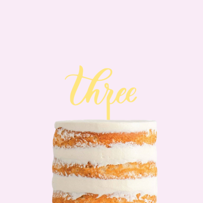 Bolo de camadas com cobertura branca e decoração amarela com a palavra 'three'