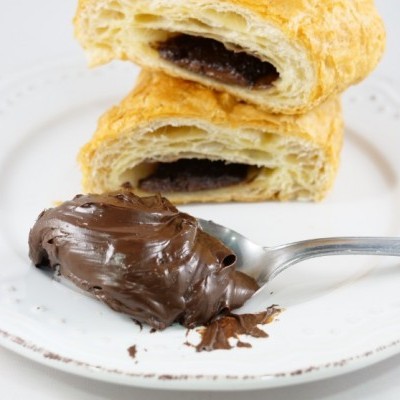 Croissants recheados com chocolate e colher com creme de chocolate no prato branco