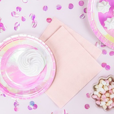 Pratos descartáveis iridescentes rosas e lilás com suspiros e mini marshmallows em fundo rosa com confetis.