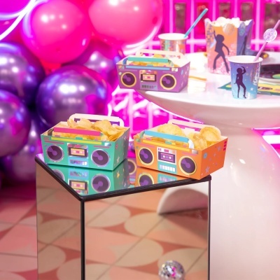 Caixas de batatas fritas coloridas e copos decorados num ambiente festivo com balões