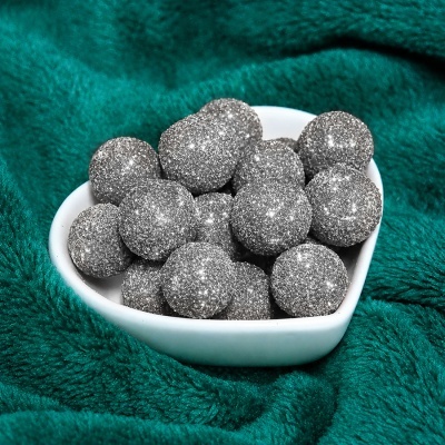Frutos secos brilhantes cinzentos em taça branca em forma de coração sobre tecido verde turquesa