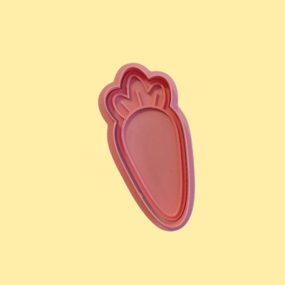 Cortador de bolachas em forma de cenoura cor-de-rosa sobre fundo amarelo