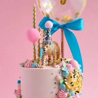 Bolo cor-de-rosa decorado com leopardo e balões coloridos