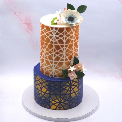 Bolo de dois andares com padrões geométricos e decoração floral