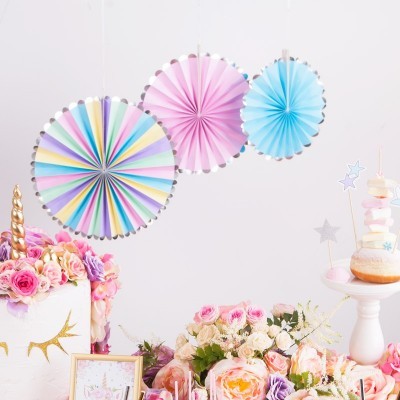Decoração de festa colorida com leques de papel, bolo de unicórnio e flores numa mesa