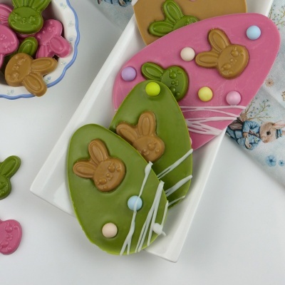 Ovos de chocolate decorados com coelhinhos em relevo, em verde, rosa e castanho com confeitos coloridos