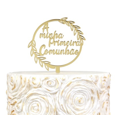 Topo de bolo dourado com texto A minha Primeira Comunhão em bolo branco decorado com rosas