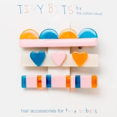 Acessórios de cabelo coloridos com formatos redondos, corações e retangulares em cartão branco.