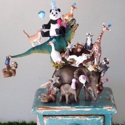 Empilhamento artístico de figuras de animais coloridos com acessórios em banco azul