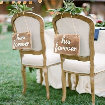 Cadeiras rústicas com quadros pendurados dizendo hers forever e his forever num jardim