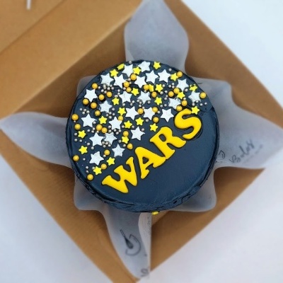 bolo decorado com estrelas e texto WARS numa caixa de cartão