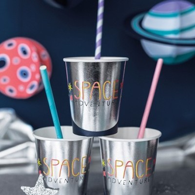 Copos metálicos prateados com texto 'SPACE ADVENTURE' e canudos coloridos em fundo com planetas