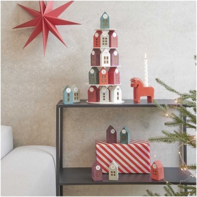 casas decorativas de madeira coloridas empilhadas e objetos natalícios sobre mesa preta